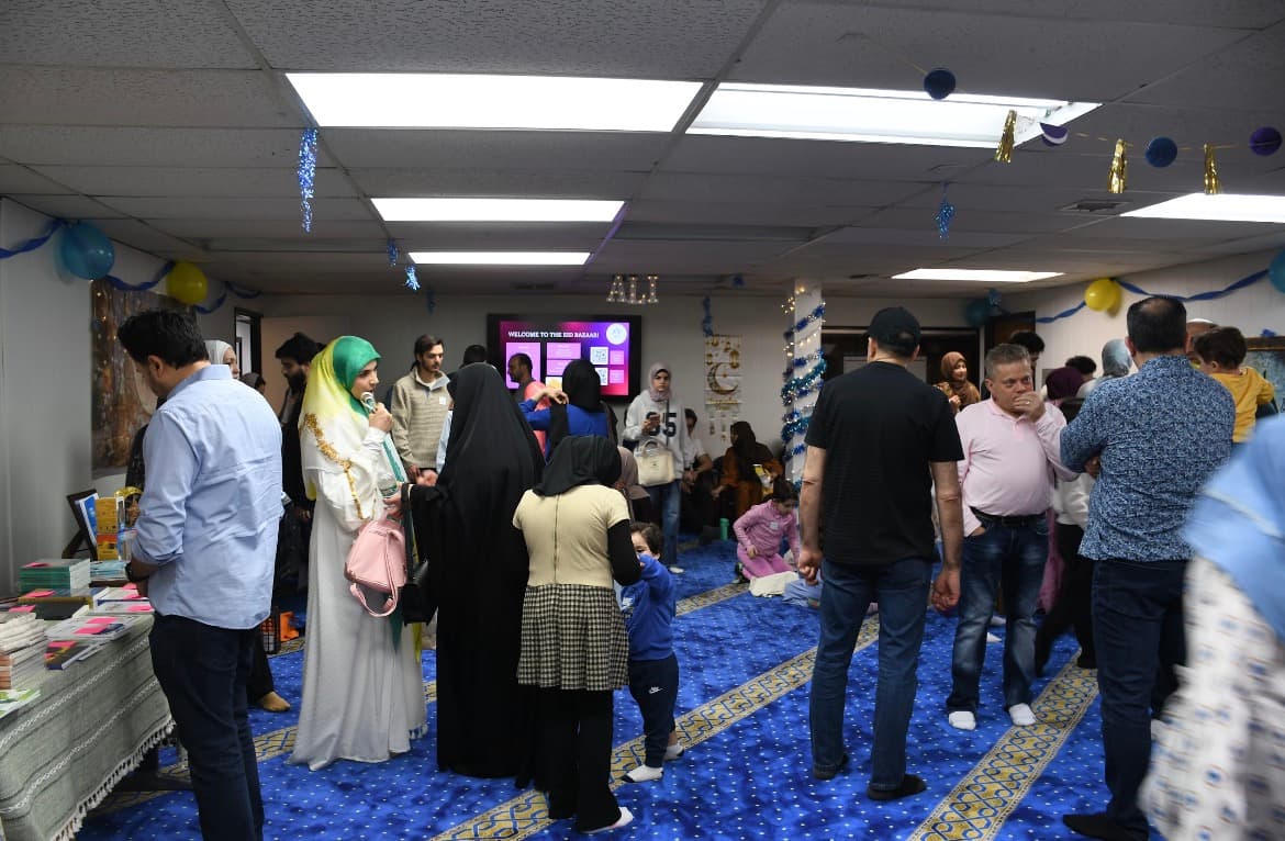 Families browsing vendor tables at the festively decorated Eid ul Fitr bazaar and carnival