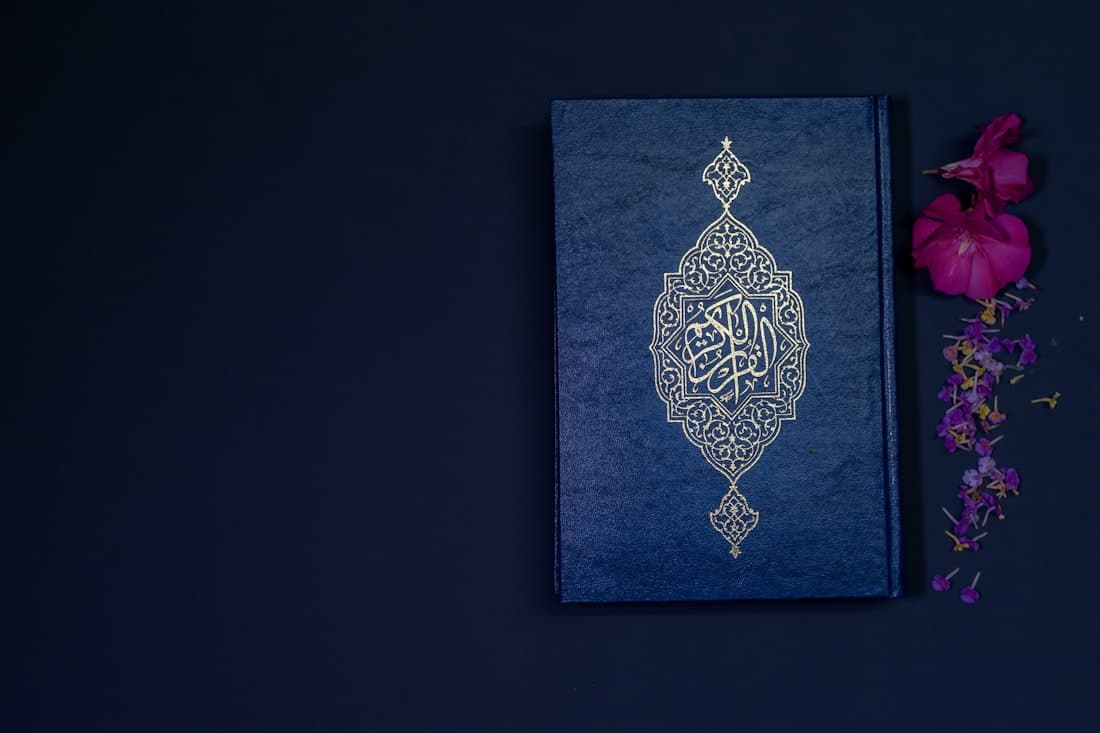 An ornate Qur'an with gold calligraphy on a deep blue cover